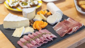 A charcuterie board with various cheeses, meats, and fruits on a slate board.
