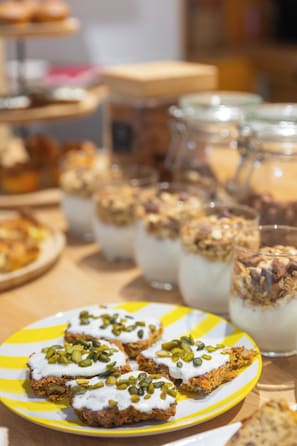 Une table sur laquelle on trouve divers aliments, notamment une assiette de pâtisseries garnies de crème et de graines, ainsi que plusieurs verres d’une boisson crémeuse.