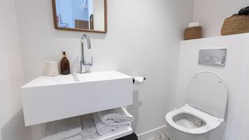 Une salle de bain moderne avec un lavabo blanc, des toilettes et un miroir.