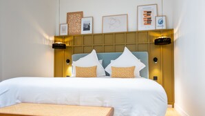 A neatly arranged hotel room with a large bed, a bedside table, and a bench. - Maison Durante (Nice)