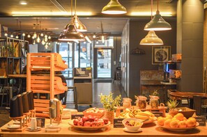 Un buffet de petit-déjeuner proposant une variété de fruits et de pains, des meubles en bois et des lampes suspendues.