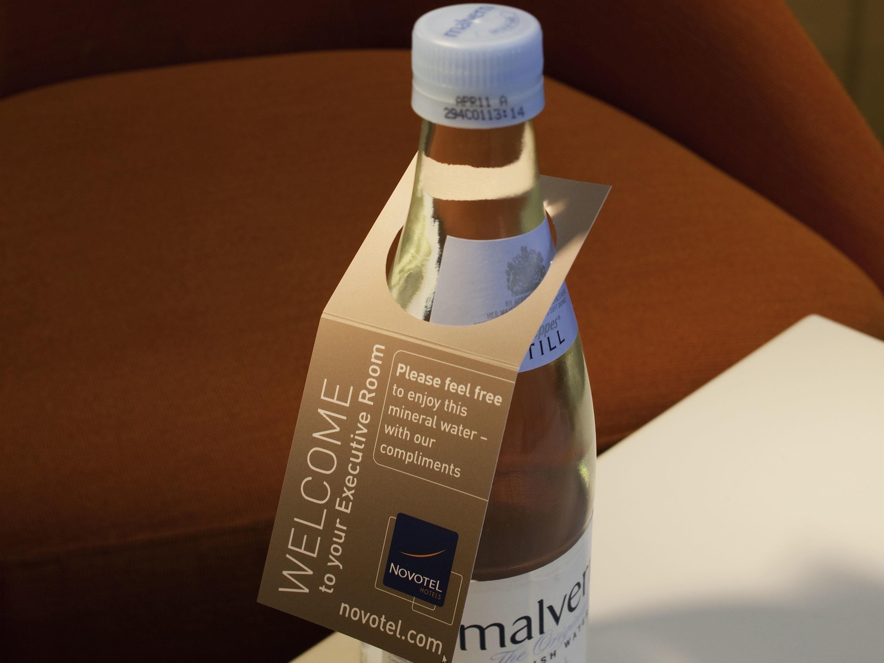 A bottle of mineral water with a welcome card attached to it.