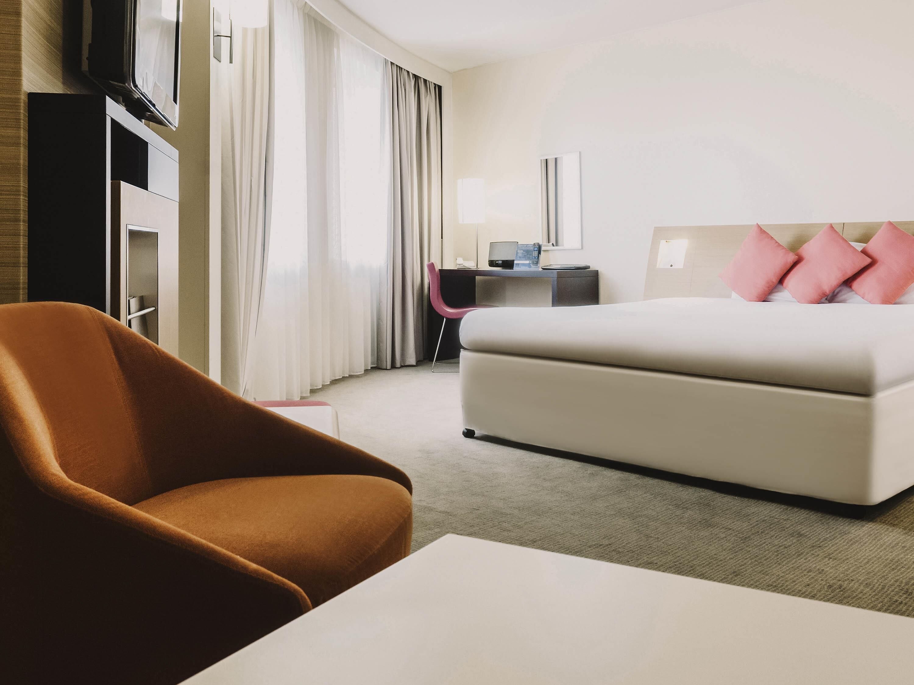 A hotel room with a bed, a desk, a chair, and a television.