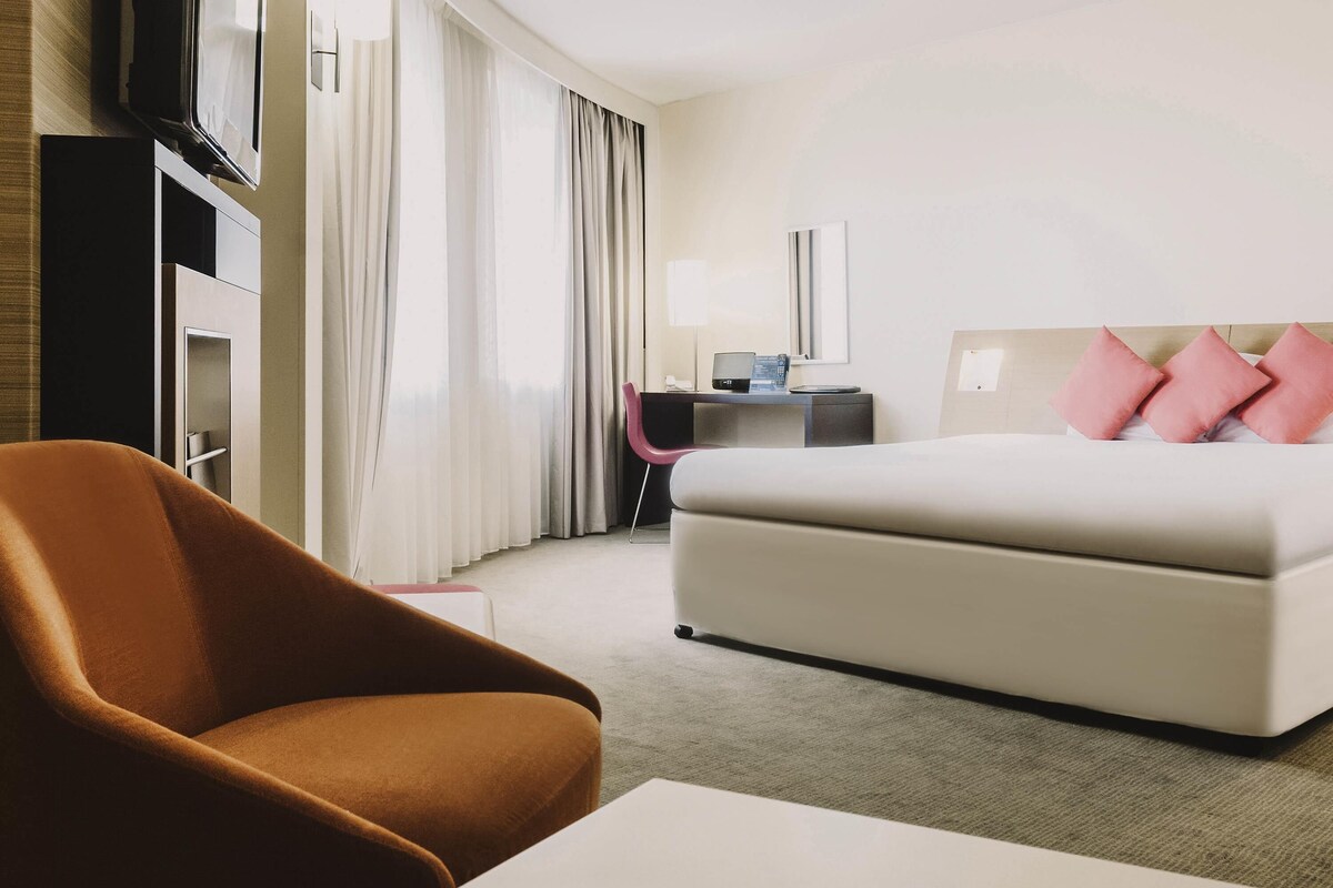 Ein Hotelzimmer mit Bett, Schreibtisch, Stuhl und Fernseher.