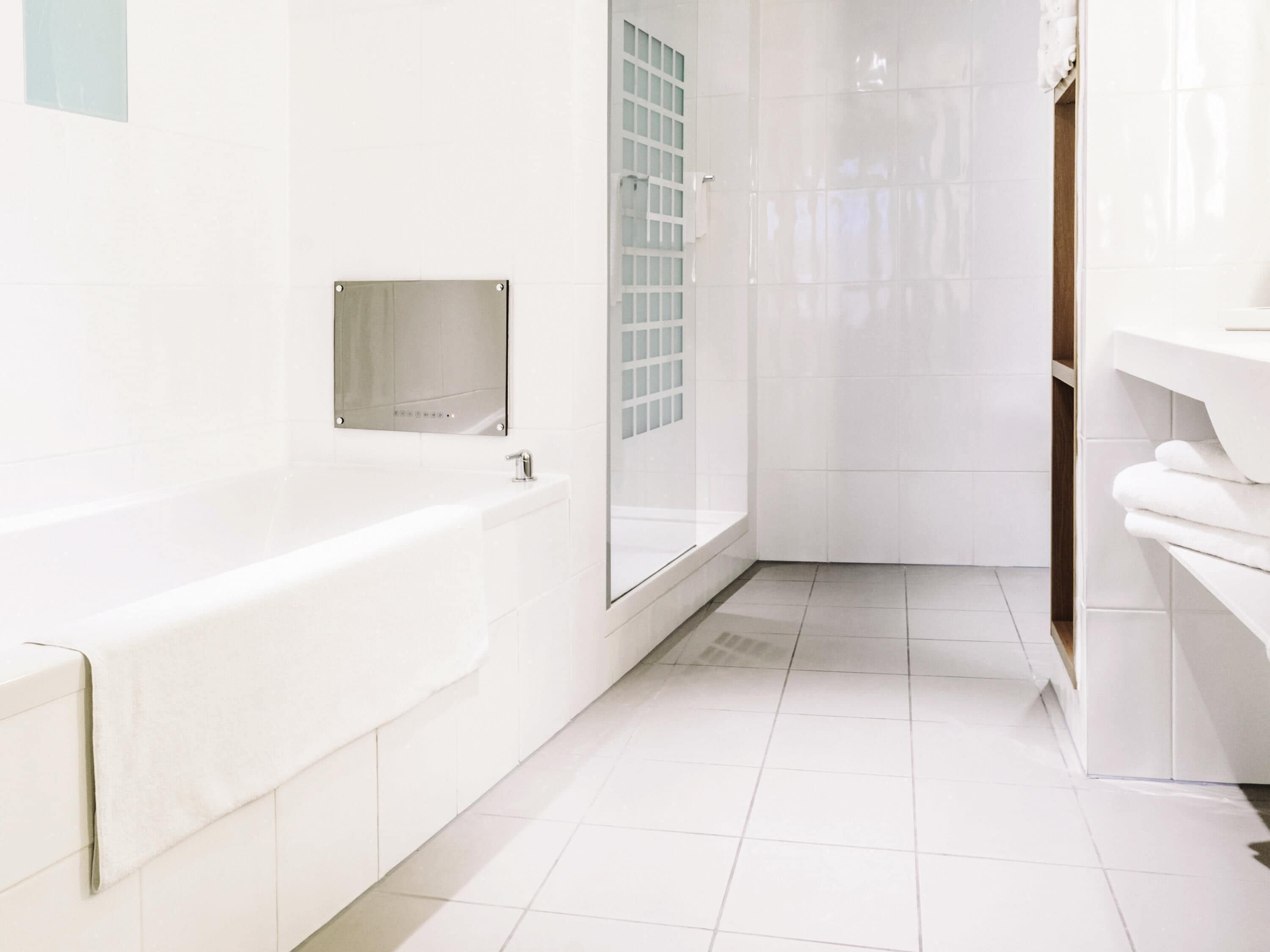 A modern bathroom with a bathtub, a glass shower enclosure, and a white tiled floor.