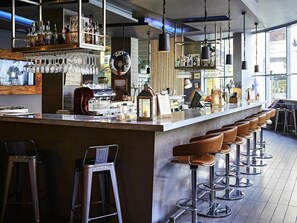 A bar area with stools, a counter, and various bottles and glasses. - Novotel Liverpool Centre (Liverpool)