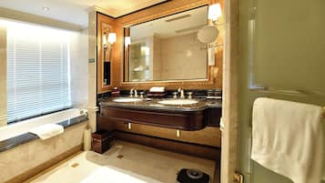A bathroom with a large mirror, two sinks, a bathtub, and a scale.