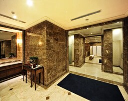 A luxurious bathroom with marble walls, a large mirror, a vanity, and a separate shower area.