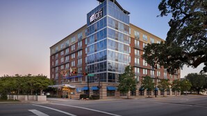 A modern hotel with a glass facade, multiple floors, and a prominent 'a loft' sign. - Aloft by Marriott Tallahassee Downtown (Tallahassee)