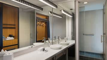 Un baño moderno con dos lavamanos, un espejo grande y una cabina de ducha de cristal.