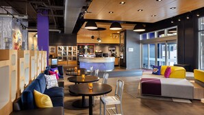 A modern lounge area with seating, tables, and a counter. - Aloft by Marriott Tallahassee Downtown (Tallahassee)