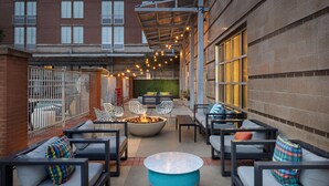 An outdoor patio area with seating, a fire pit, and string lights. - Aloft by Marriott Tallahassee Downtown (Tallahassee)