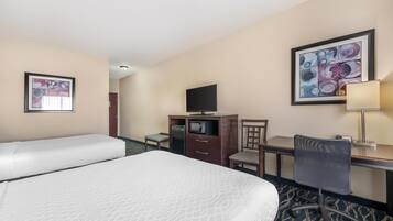 A hotel room with two beds, a desk, a chair, a television, and artwork on the walls.