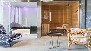 A modern hotel room with a glass-enclosed shower, a wicker sofa, and a small round table. - Best Western Plus Europe Hotel (Brest)