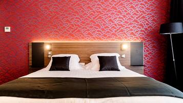 A hotel room with a large bed, two bedside tables, and a red patterned wall.