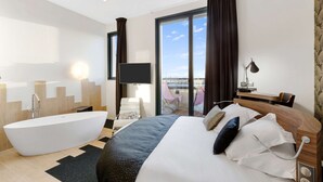 A modern hotel room with a large bed, a bathtub, a flat-screen TV, and a balcony with a view. - Best Western Plus Europe Hotel (Brest)