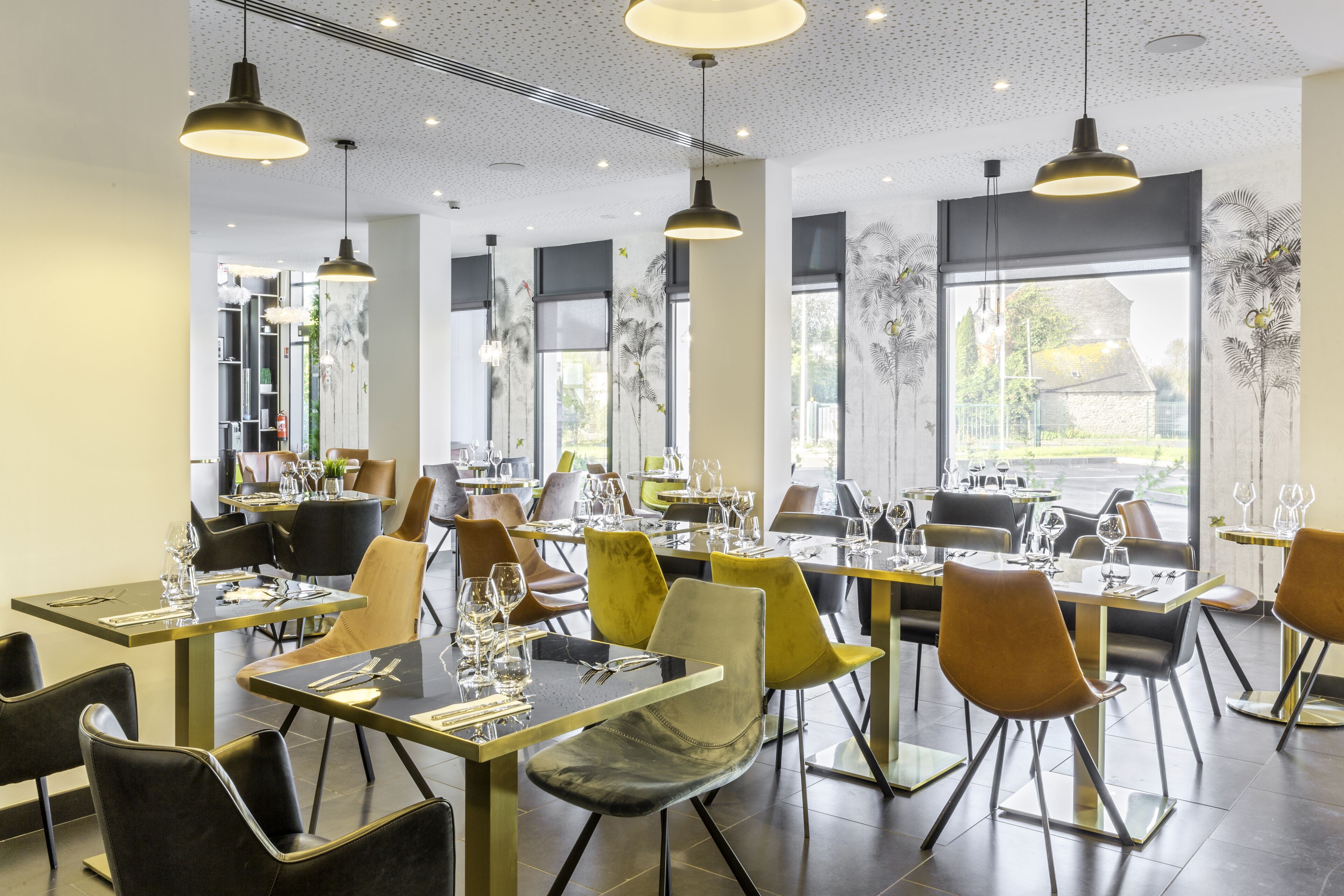 Un restaurante moderno con mesas altas, sillas, iluminación colgante y ventanas amplias con vistas.