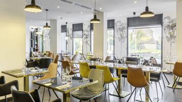 Un restaurante moderno con mesas altas, sillas, iluminación colgante y ventanas amplias con vistas.