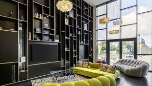 A modern living room with a large TV, yellow sofa, and a unique armchair. - Best Western Plus Europe Hotel (Brest)