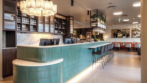 A modern bar area with a teal counter, bar stools, and a large pendant light. - Thon Hotel Ullevaal Stadion (Oslo)