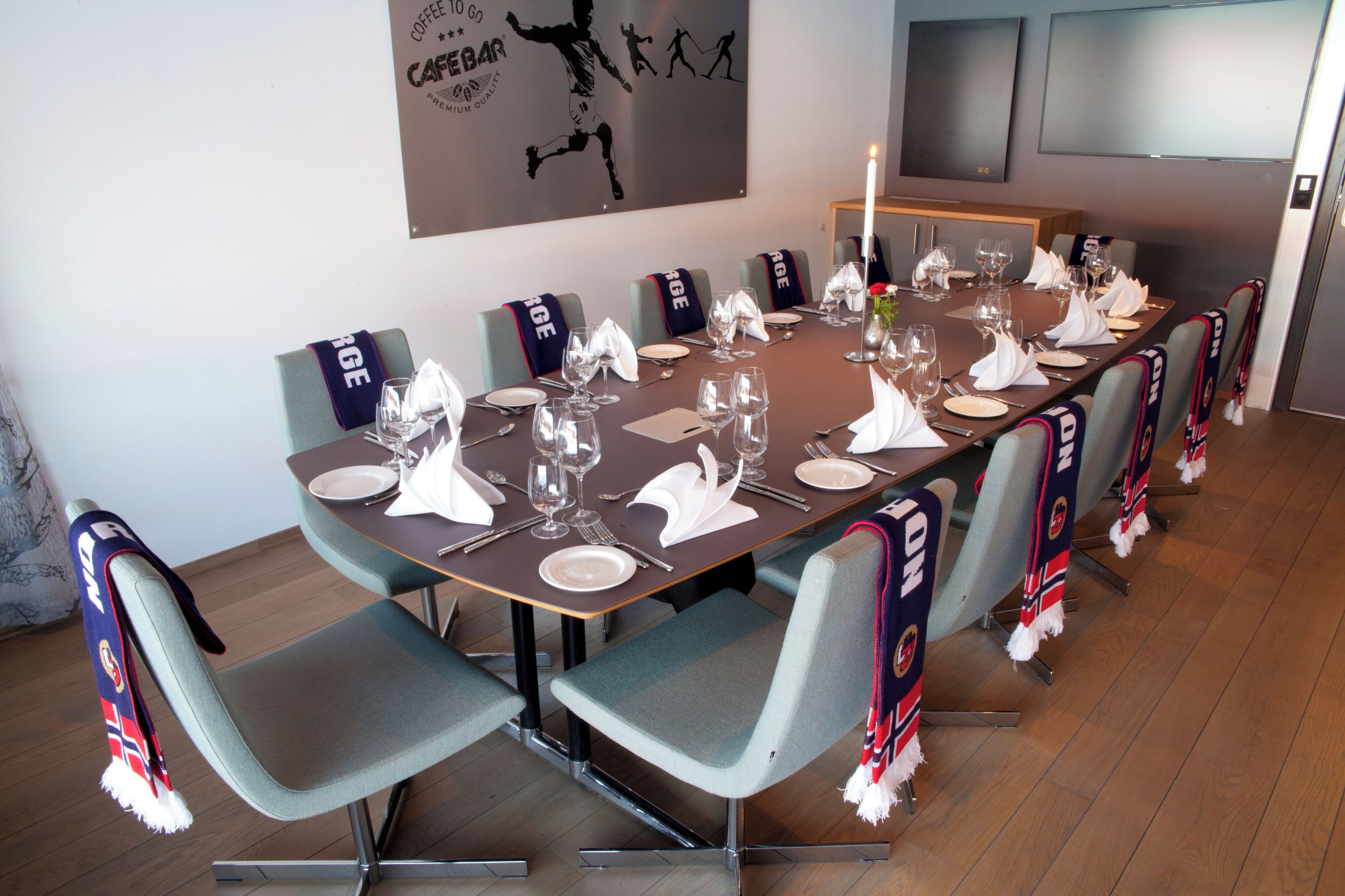 A conference room with a long table set for a meeting, equipped with chairs, plates, glasses, and cutlery.