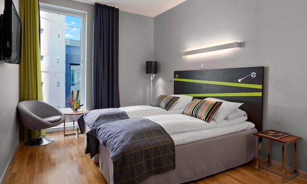A modern hotel room with a large bed, a desk, a chair, and a view of the outside. - Thon Hotel Ullevaal Stadion (Oslo)