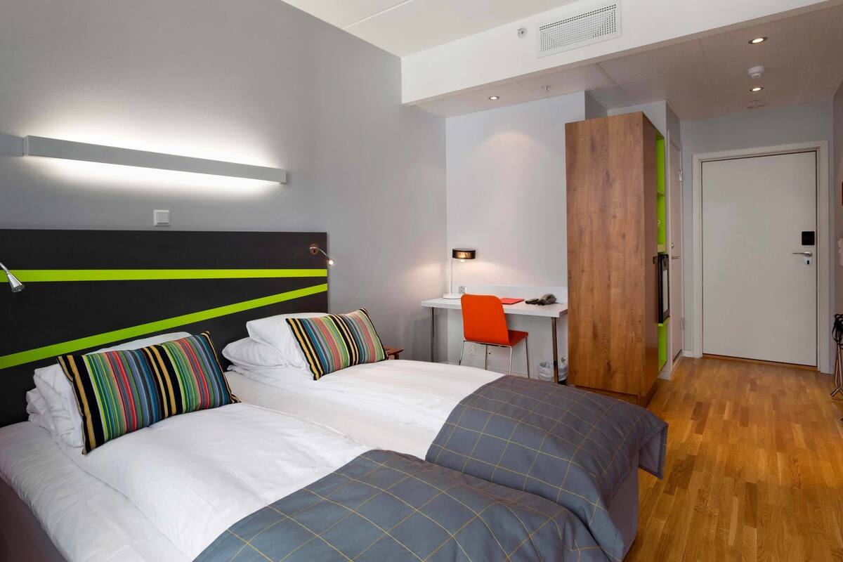 A modern hotel room with a large bed, a desk, and a separate sleeping area.
