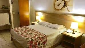 Une chambre d’hôtel comprenant un lit, deux lampes de chevet, une table de chevet, une armoire en bois et une œuvre d’art accrochée au mur.