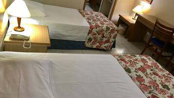 Habitación de hotel con dos camas, un escritorio, una silla, una lámpara y un teléfono.