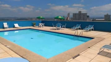 Relax by the rooftop pool surrounded by a deck and lounge chairs, offering a tranquil escape in the heart of the city.