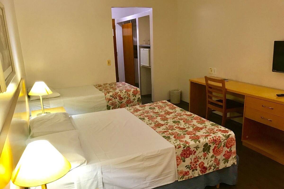 Een kamer met twee bedden, een bureau, een stoel en een televisie.