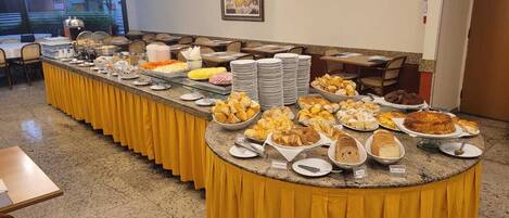 Montaje de bufé con diversos alimentos y un mantel amarillo.