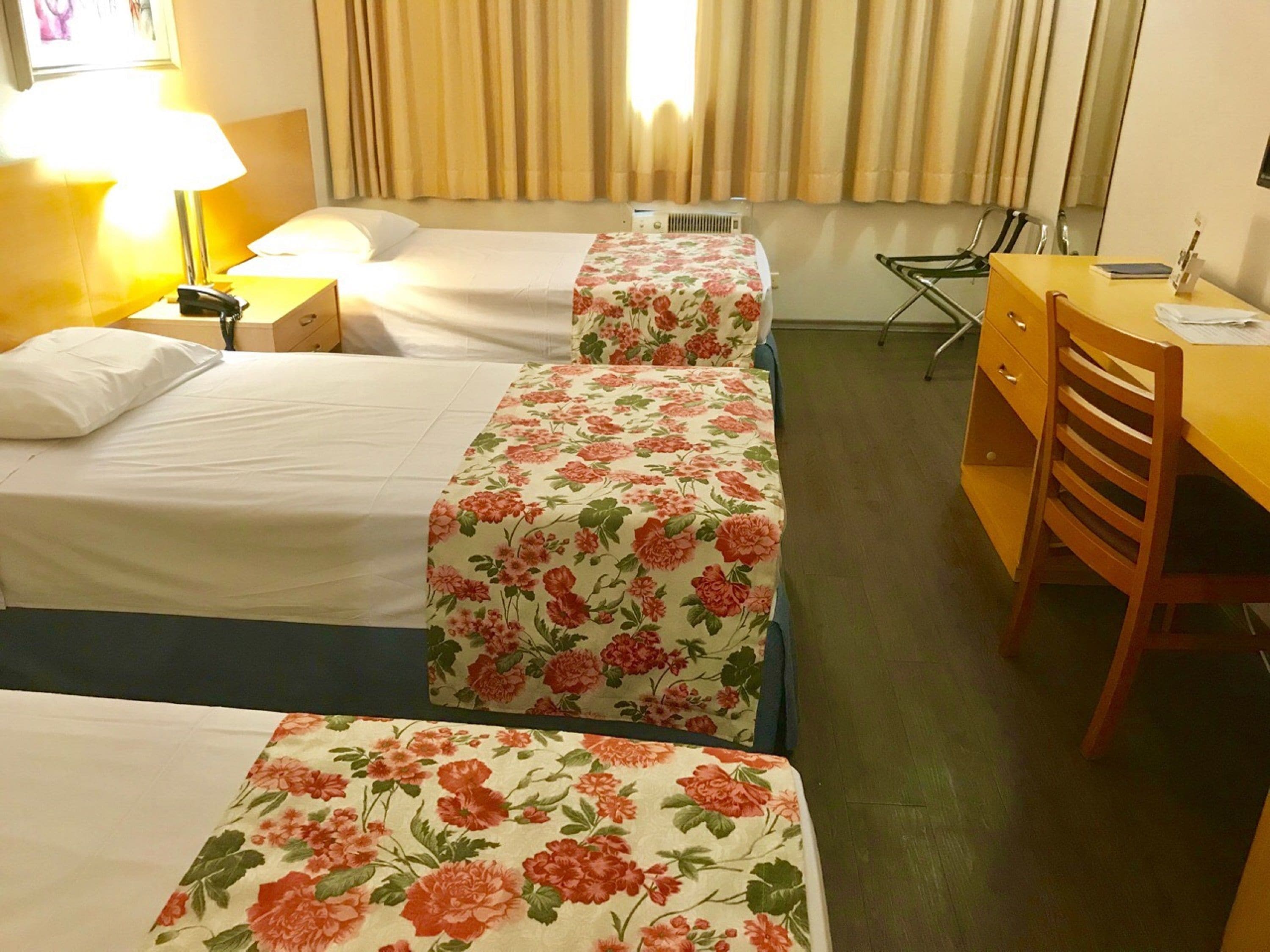 Une chambre d’hôtel avec deux lits, un bureau et une chaise.