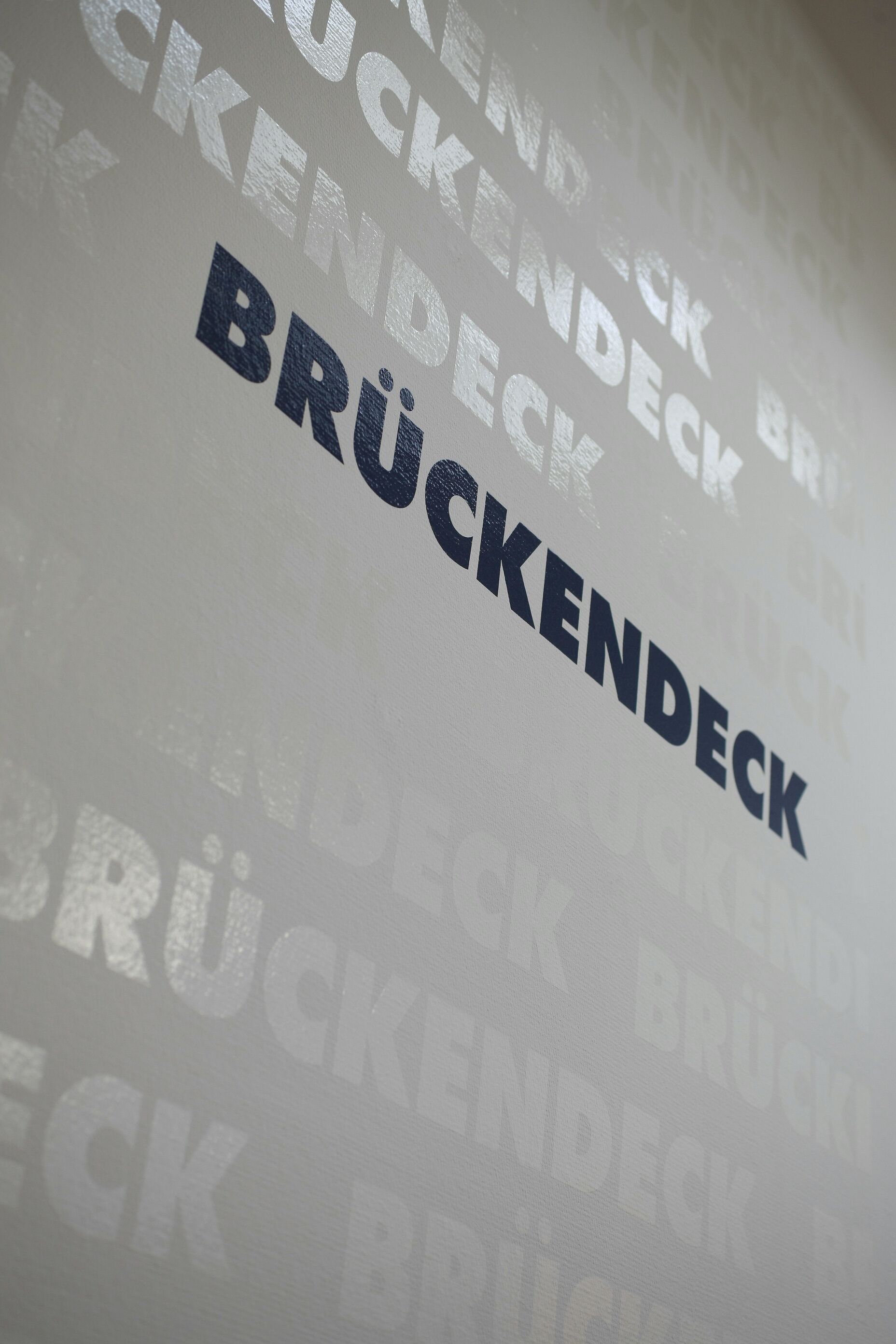 A wall with repeated text 'BRÜCKENDECK' in varying sizes and orientations.