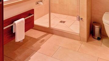 A modern bathroom with a glass-enclosed shower, a wooden vanity, a white sink, and a toilet.