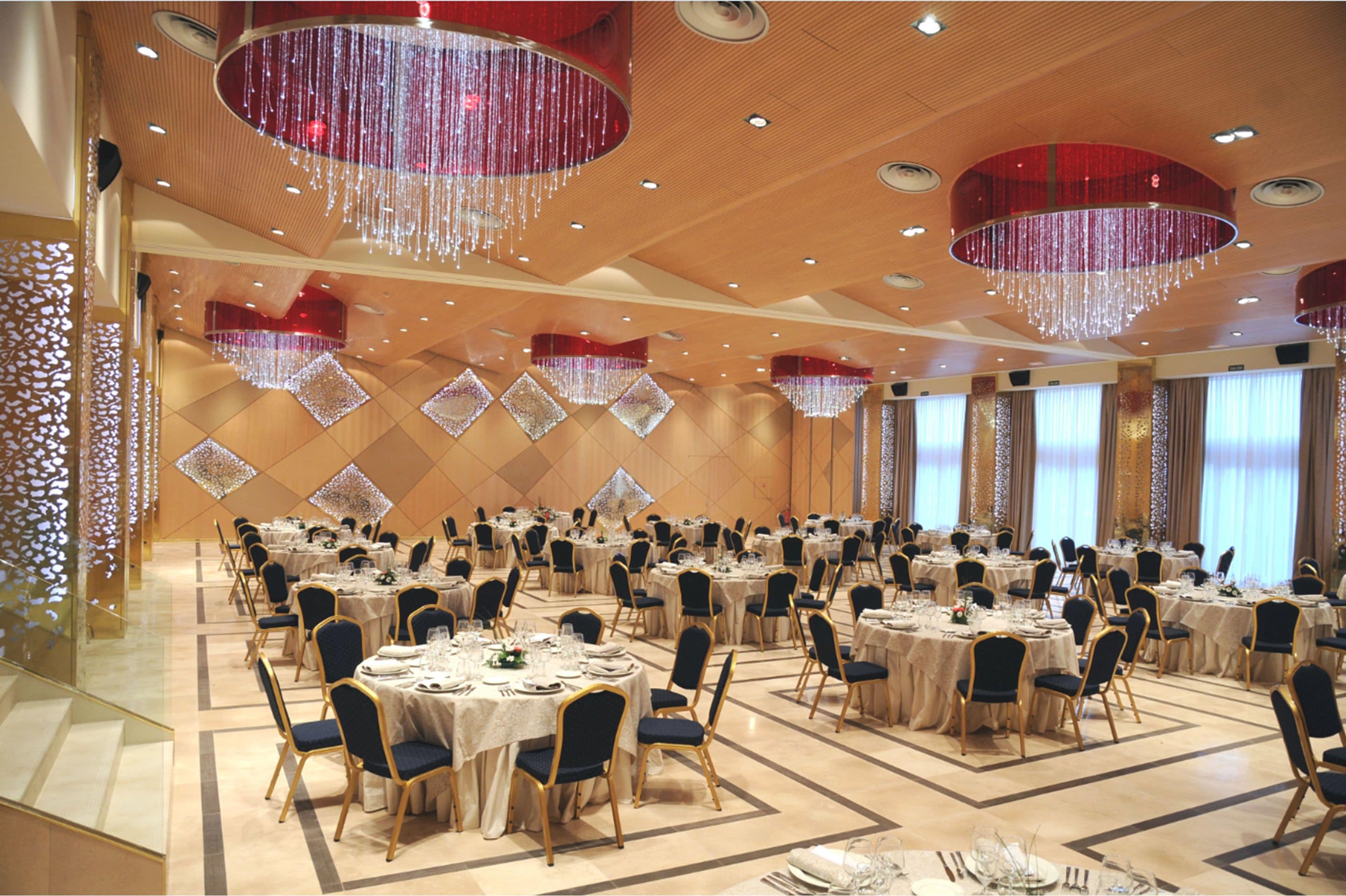Un salón de banquetes con mesas redondas, sillas y candelabros.
