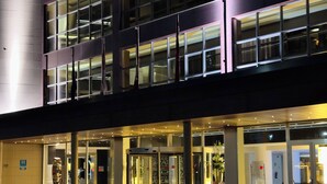 A modern hotel entrance with glass doors, a revolving door, and a well-lit facade. - Hotel Palacio Albacete & SPA (Albacete)