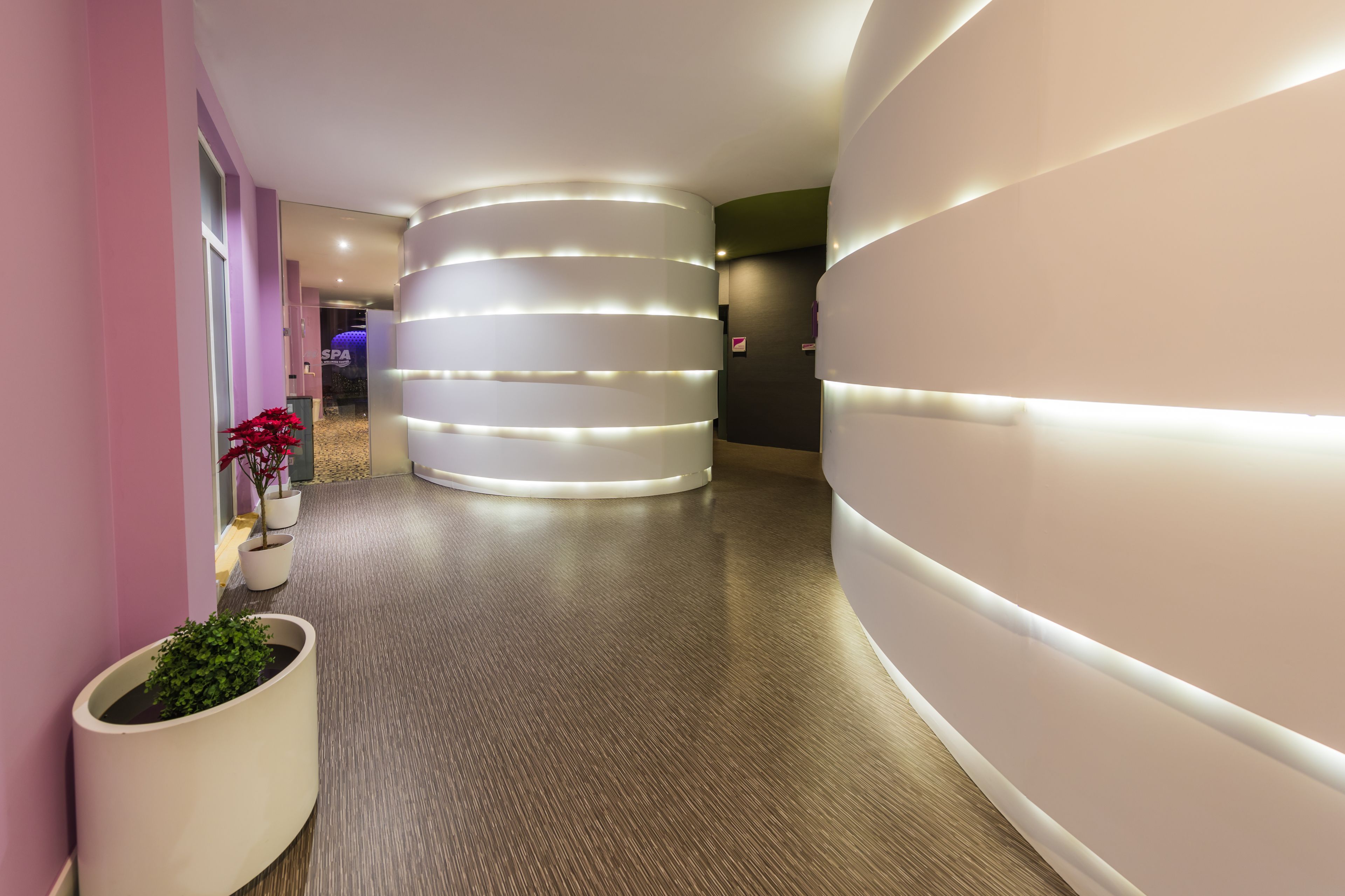 A modern hallway with a curved wall and a large, illuminated cylindrical structure.