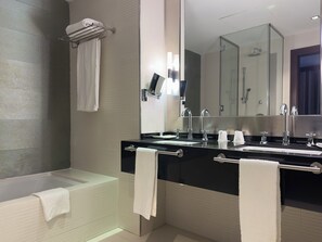 A modern bathroom with a bathtub, two sinks, and a large mirror. - Hotel Palacio Albacete & SPA (Albacete)