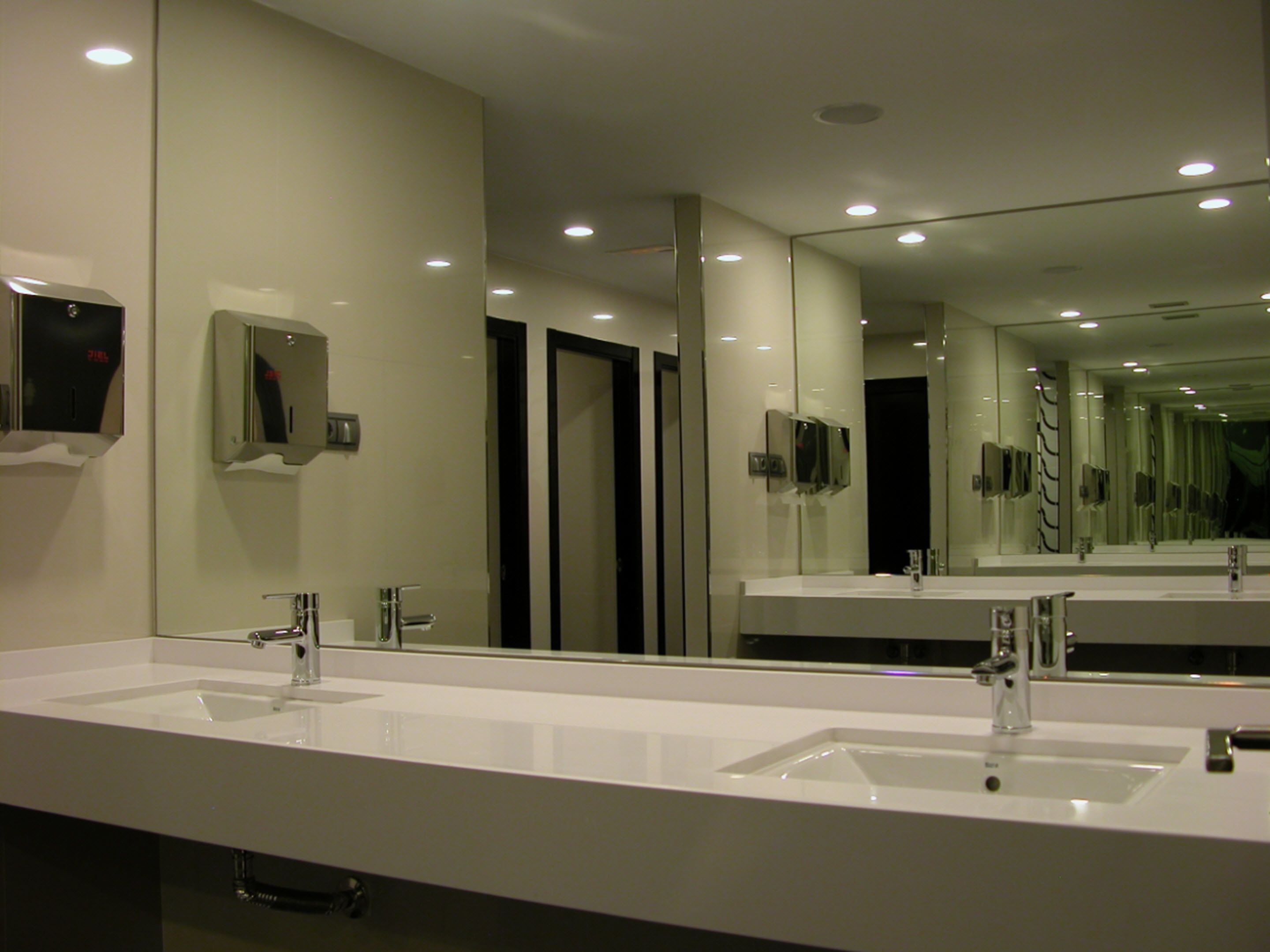 A modern bathroom with two sinks, a large mirror, and recessed ceiling lights.