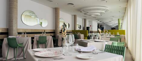 A restaurant with round tables, green chairs, and a modern ceiling design.