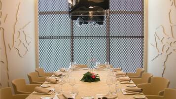 A dining area with a long table set for a meal, chairs around it, and a decorative wall with a geometric pattern.