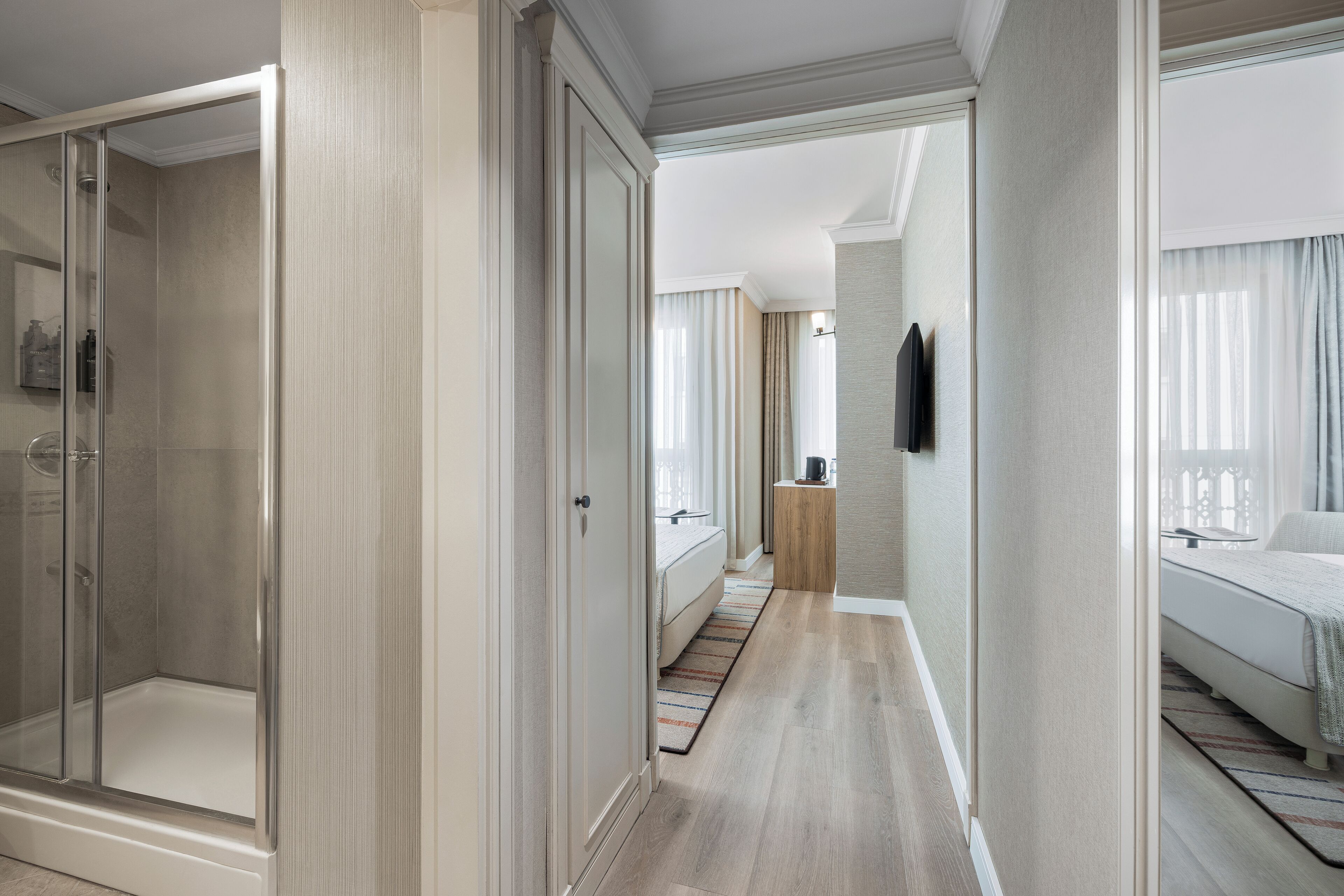 A hotel room with a walk-in closet, a shower, a bed, and a television.