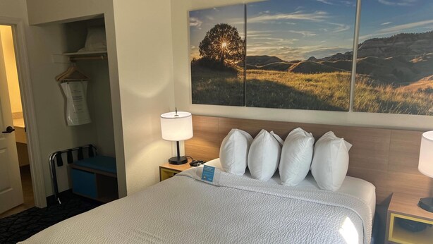 Une chambre d’hôtel avec un grand lit, une table de chevet avec une lampe, un bureau avec une chaise et une armoire.