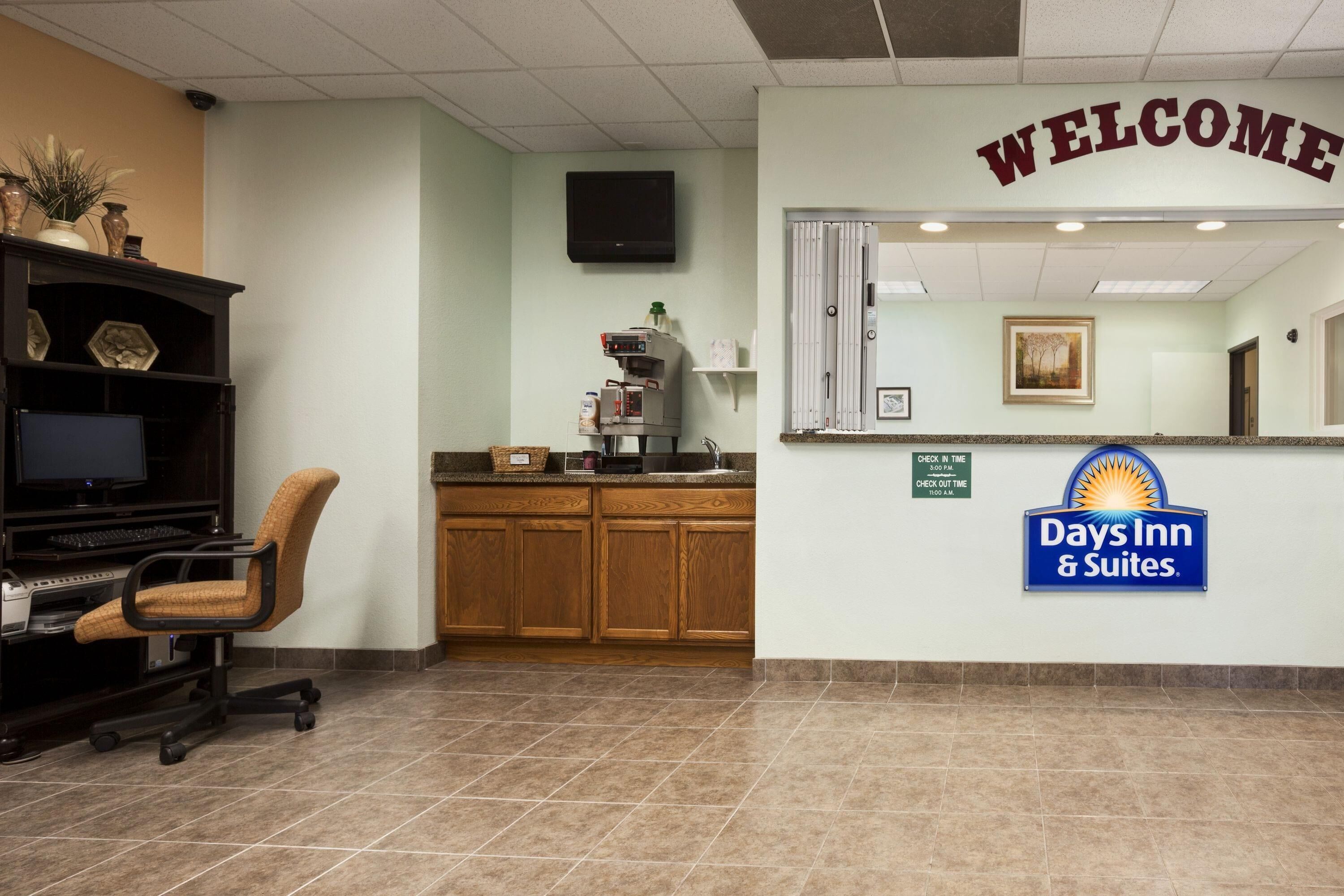 A reception area with a 'WELCOME' sign, a reception desk, a coffee machine, a computer, and a chair.
