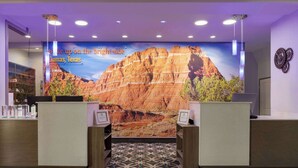 A reception area with a large wall mural of a mountain landscape, two reception desks, and a patterned floor mat. - La Quinta Inn & Suites by Wyndham Dumas (Dumas)