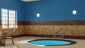 An indoor swimming pool with a blue tiled wall, a window, and a seating area with chairs. - La Quinta Inn & Suites by Wyndham Dumas (Dumas)