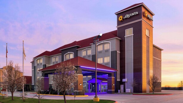 A La Quinta hotel with a modern design, featuring a prominent tower with the hotel name, a covered entrance, and a well-maintained lawn area. - La Quinta Inn & Suites by Wyndham Dumas (Dumas)