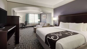 A hotel room with a large bed, a desk, a chair, a TV, and a window with curtains. - La Quinta Inn & Suites by Wyndham Dumas (Dumas)