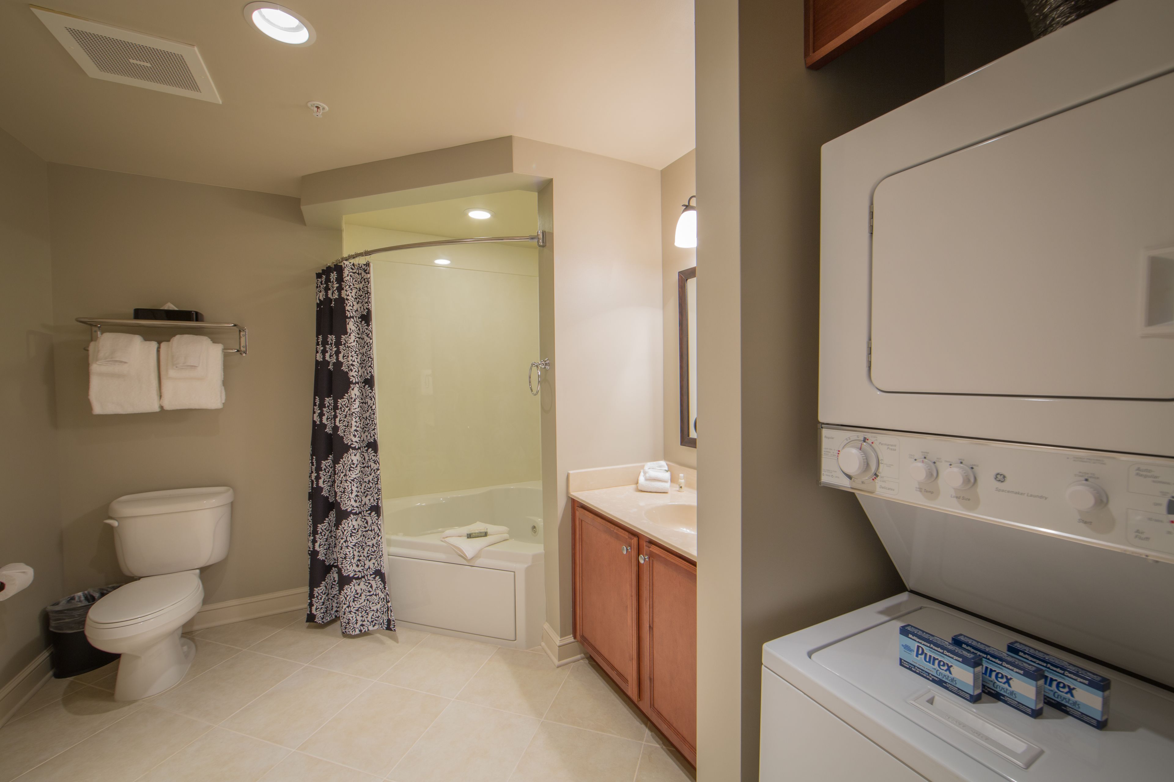 A bathroom with a toilet, shower, and a washing machine.